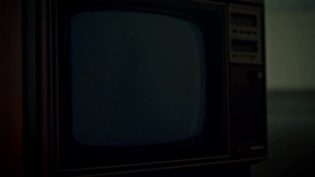 Slow pan tracking shot of vintage television screen flickering then cutting to blackout in dim living room interior with grid pattern on cathode ray tube