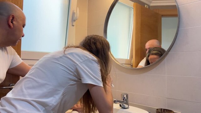 Pareja lav&aacute;ndose los dientes frente al espejo del ba&ntilde;o