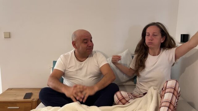 Pareja despertando y estir&aacute;ndose en la cama