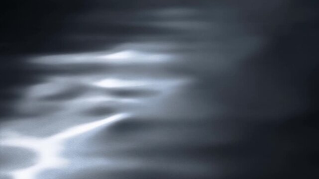 Slow motion close up of water surface ripples and shimmering light reflections on dark calm lake or pool with subtle tracking movement