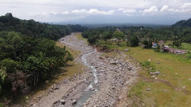 Agam, Indonesia - April 3rd 2026: Aerial Drone Slow Push-in Toward Widened Riverbed After Salareh Aia Flash Flood: Close-up Detail of Massive Boulders and Rocks in Disaster Impact Zone