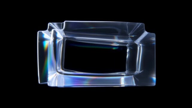 Slow dolly in with subtle pan of rectangular clear glass ashtray rotating and shifting on black seamless studio background close up product reveal