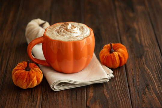 Cozy pumpkin latte in a pumpkin shaped latte mug with whipped cream and spices