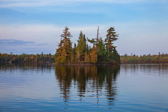 Small island with pines on a calm northern Minnesota lake at sunset during autumn