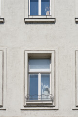 Fototapeta premium The light grey facade of a historic building in Zagreb features windows with decorative stone frames and small wrought iron details