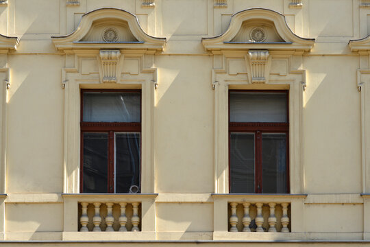 The creamy yellow facade of a historic building in Zagreb features windows with decorative stone pediments and small stone balustrades