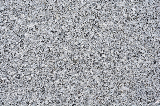 A close up shot captures the detailed grainy and speckled texture of a natural grey granite stone surface