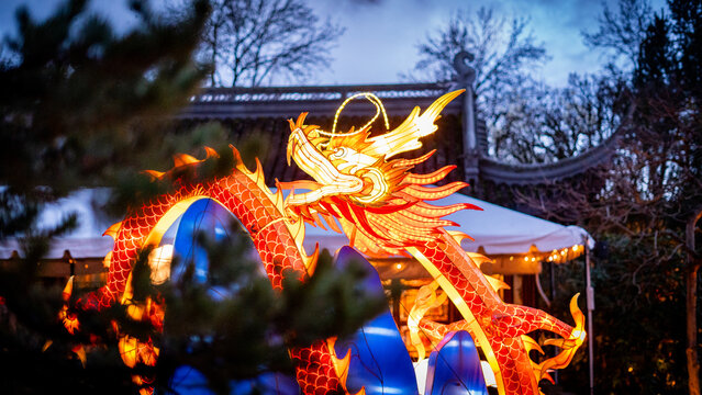 View of a glowing dragon lantern and traditional architecture at Lan Su Chinese Garden during a festival in Portland, Oregon, United States.
