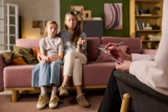 Caucasian mother with girl discussing concerns during family therapy session while counselor taking notes. Useful for mental health, parenting support, counseling marketing