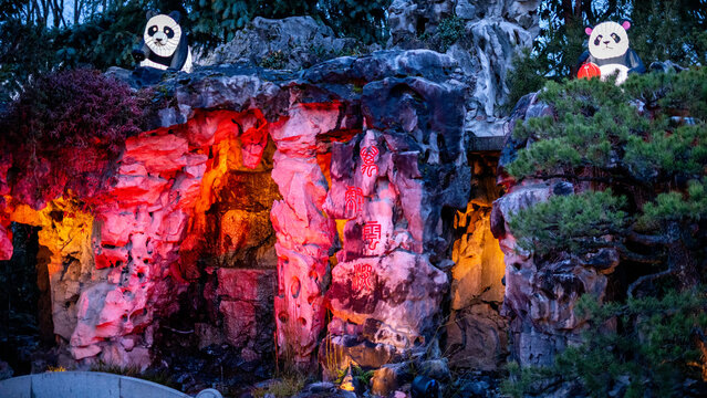View of the illuminated rockery at Lan Su Chinese Garden featuring panda lanterns and Chinese calligraphy on stone Portland, Oregon, United States.