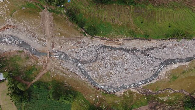 Agam, Indonesia - April 3rd 2026: Aerial Top View Drone Tracking Left of Emergency Bridge and Widened River After Salareh Aia Flash Flood: Boulders, Debris, and Vital Rural Village Connectivity Link