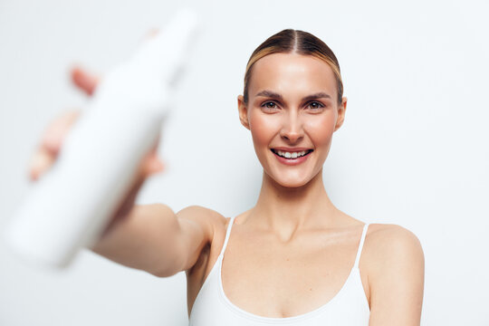 Smiling woman, skincare, face cream, white background, self care, close up, studio lighting, wellness, she smiles while applying white cream, clean studio setup, soft light