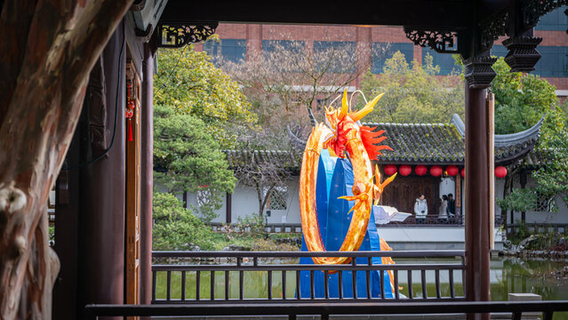 View of the Lan Su Chinese Garden featuring a large dragon lantern, traditional architecture, and red lanterns by the pond in Portland, Oregon, United States.