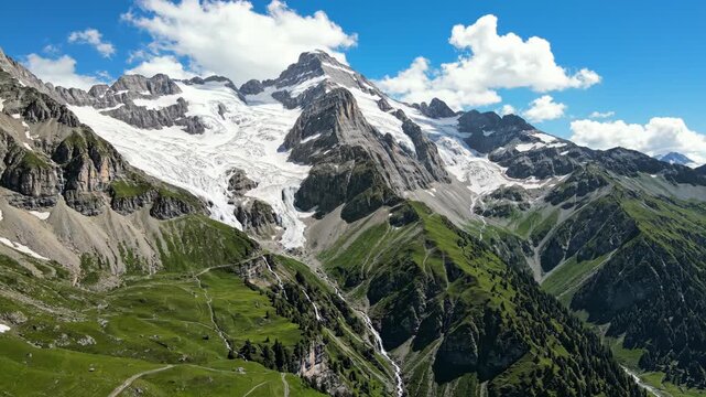 Majestic alpine mountains with snow, waterfalls and green pastures
