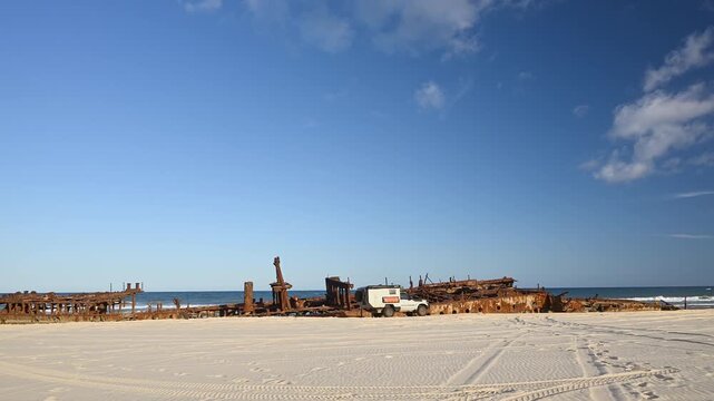 Off-road vehicle parked by SS Maheno shipwreck on Fraser Island K'gari, Queensland, Australia. Iconic rusting wreck on sandy beach, popular 4WD travel and adventure destination.
