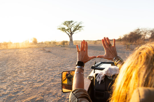 woman framing a baobab tree with her hands, Makgadikgadi National Park, Botswana, Africa