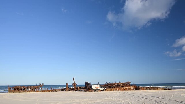 Off-road vehicle parked by SS Maheno shipwreck on Fraser Island K'gari, Queensland, Australia. Iconic rusting wreck on sandy beach, popular 4WD travel and adventure destination.