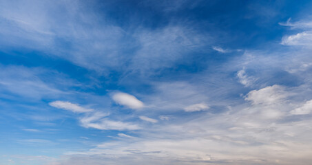 Naklejka premium heaven skies blue and clear, with thin, puffy, transparent clouds. and moon is visible through them. sun shines brightly, making sky even brighter. scene is peaceful and serene