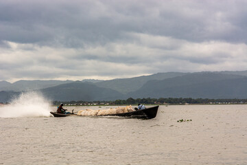 Obraz premium Motorized boat loaded with goods speeding across Inle Lake