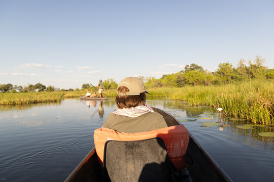 child in traditional makoro boat navigating the Okavango Delta, Botswana, Africa