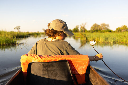 child in traditional makoro boat, navigating the Okavango Delta, Botswana, Africa