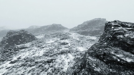 Snow dusted rocky mountain ridges under a grey sky, snowflakes drifting in a cold, misty high altitude wilderness, evoking harsh, serene winter solitude and blizzard weather