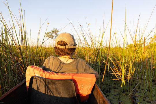 child in traditional makoro boat, navigating the Okavango Delta, Botswana, Africa