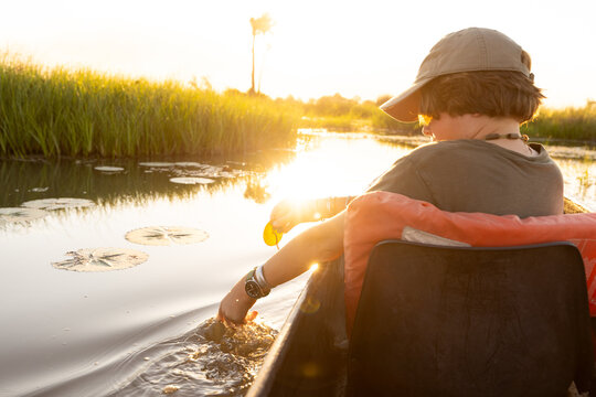 child in traditional makoro boat, navigating the Okavango Delta, Botswana, Africa