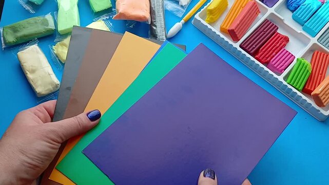 Hands are sorting through colored paper - preparation for the creative process