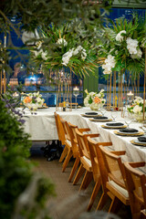 Obraz premium Elegant dinner setup in a garden space. Tables are arranged in a garden area with flowers and decorative items.