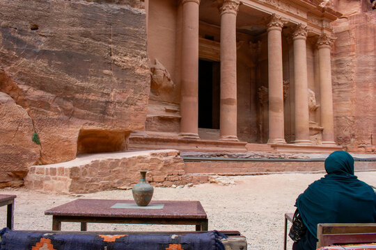 Back View of Woman looking at The Khazneh Palace, the Pharaoh's Treasury, is a Nabatean temple from the Hellenistic period in Ancient city of Petra in Jordan.