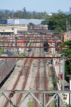 Railway line with parallel tracks and a train stopped on a side track, possibly used for waiting, maintenance, or operational control, surrounded by urban infrastructure and vegetation.