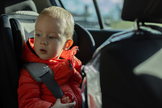 Portrait of cute little boy sitting in a children car seat. Child transportation safety. 