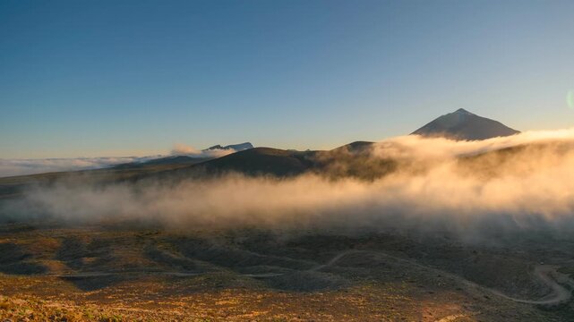 4K time-lapse of golden flowing clouds around mountains at sunrise