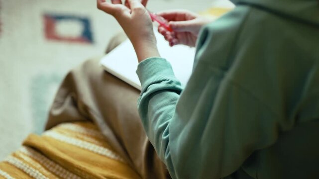 Smart Little Girl in Big Glasses Writing in Notebook while Sitting on Couch with Stack of Books &mdash; Cinematic 4K 10-bit