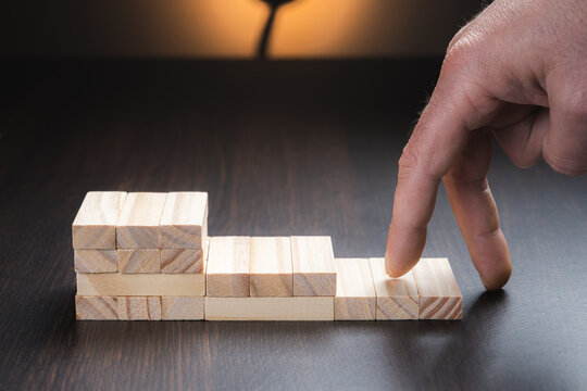 Goals of success and business progress, represented by a hand climbing a ladder of wooden cubes. Concept of success in large and medium-sized companies.