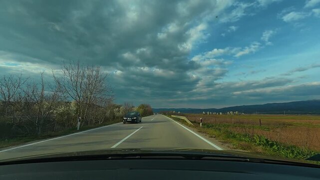 Drive along winding country road under dramatic sky. Serbia, near Leskovac