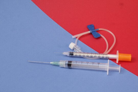 Jeringas para colocar tratamiento m&eacute;dico, puestas sobre un fondo azul y rojo.