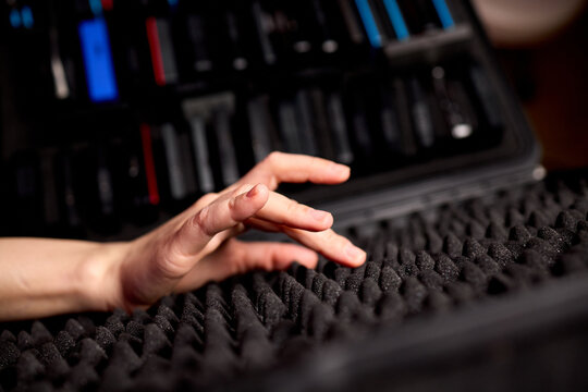 Mixer adjusting nearby. Adjusting audio mixer amid soundproofing in studio environment. Focus on live recording setup with tactile controls and soundproofing in studio setting