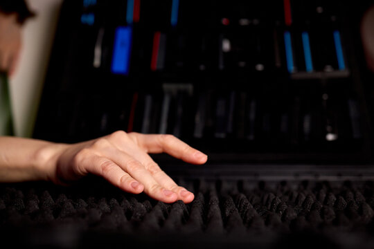 Mixer adjusting nearby. Adjusting audio mixer amid soundproofing in studio environment. Focus on live recording setup with tactile controls and soundproofing in studio setting