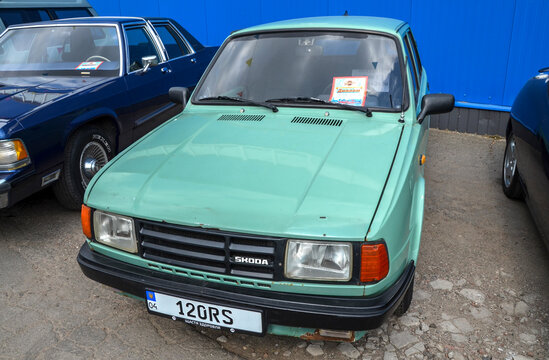 Light green Skoda 120 sedan is parked at an outdoor event. This rear engine classic features rectangular headlights, and black plastic grille
