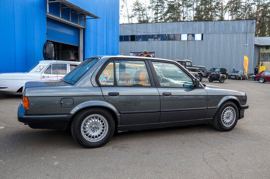 Classic grey BMW 3 Series (E30) sedan with its iconic boxy silhouette and multi spoke alloy wheels, it remains a celebrated icon of 1980s European automotive culture