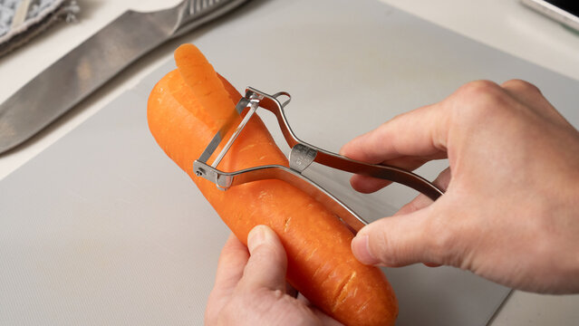 Close-up of Carrot Being Peeled with Peeler Showing Orange Flesh &ndash; Food Prep