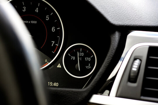 Tachometer and oil temperature gauge on a modern car dashboard, close-up view of illuminated instrument panel with precise indicators and digital display.