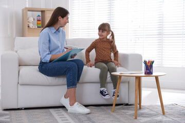 Obraz premium Professional psychologist working with little girl on sofa indoors