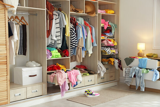 Many different messy clothes in wardrobe indoors