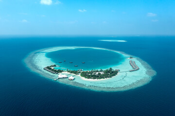 Wide aerial view of Maldives resort island surrounded by lagoon with distant atolls in the ocean © Krzysztof Bargiel