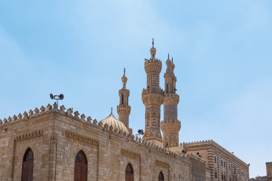 View of Al-Azhar Mosque featuring its ornate stone minarets and central dome under a clear blue sky in El-Darb El-Ahmar, Cairo Governorate, Egypt.