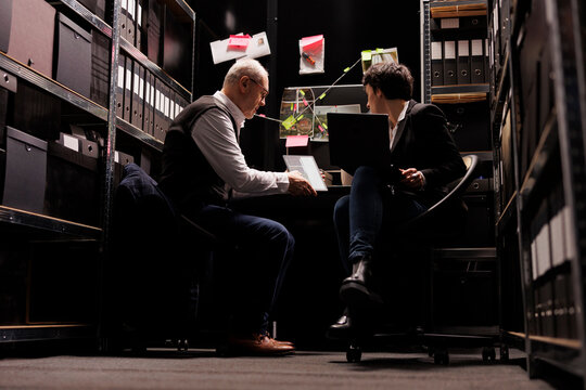 Elderly police officer examining crime evidence files, discussing criminology report with fbi agent. Investigators analyzing victim report discovery confidential information. Investigation concept