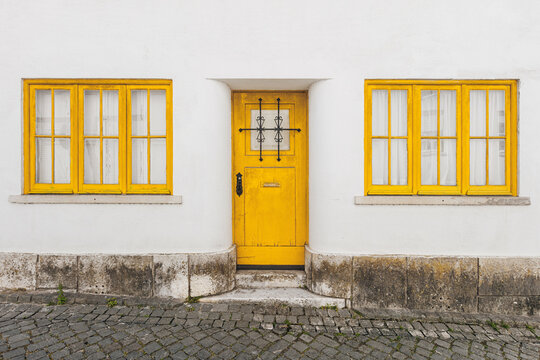 A fragment of the old Portuguese residential building facade with a yellow door and windows.	